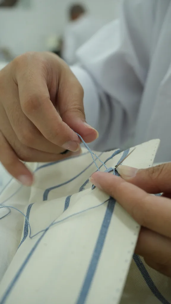 Laxmi master tailor hand-stitching bespoke suit details at the atelier in Jakarta since 1949