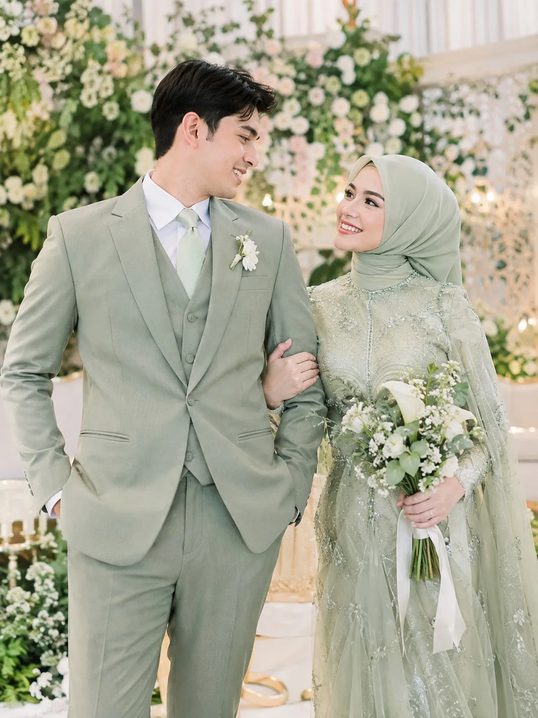 Groom in a sage green bespoke three-piece wedding suit by Laxmi Tailors, matched to the bride's sage hijab and gown